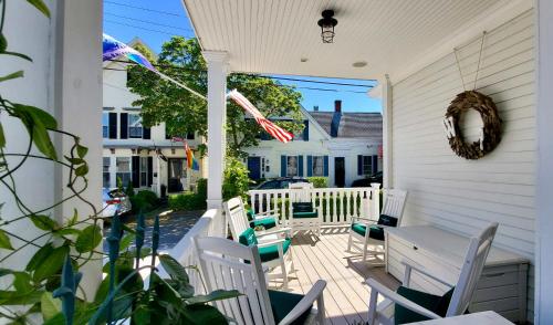 um alpendre com cadeiras brancas e uma mesa em White Porch Inn em Provincetown