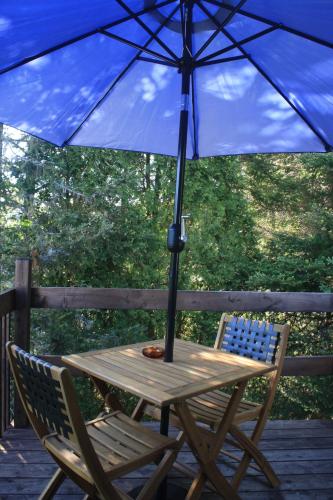 a wooden table and chair under an umbrella on a deck at Au Sommet du Fjord in Sacré-Coeur-Saguenay
