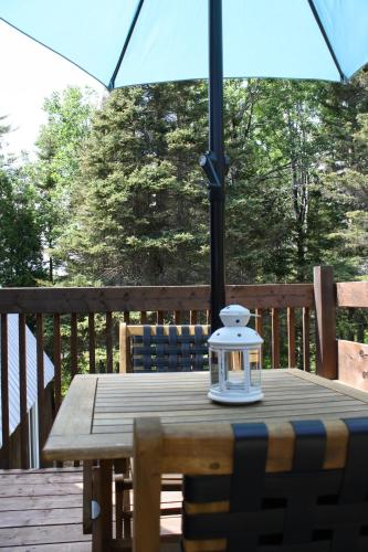 a wooden table with an umbrella on a deck at Au Sommet du Fjord in Sacré-Coeur-Saguenay