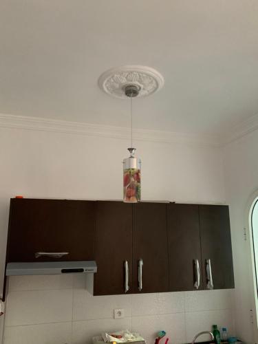 a kitchen with brown cabinets and a white ceiling at Résidence Lilia Al Jabal M’diQ in M'diq