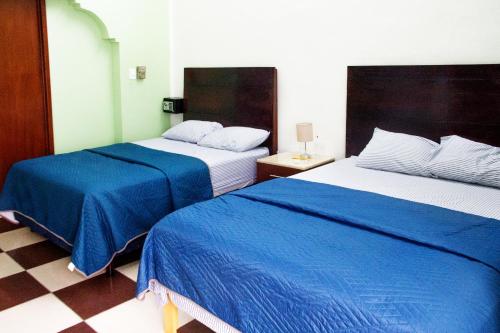 a hotel room with two beds with blue sheets at Casa NE in Mérida