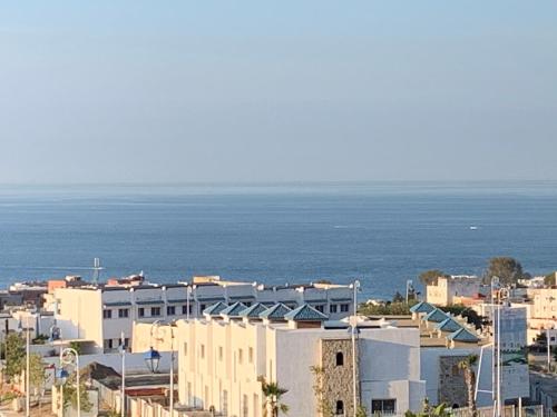 a city with buildings and the ocean in the background at Résidence Lilia Al Jabal M’diQ in M'diq