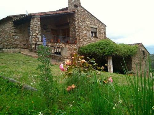 an old stone house in a field of grass at Apartamentos Rurales La Macera **** in Valencia de Alcántara