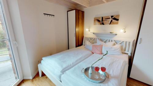 ein Schlafzimmer mit einem weißen Bett und einem Tablett darauf in der Unterkunft Feriendorf Südstrand Haus 40 in Pelzerhaken