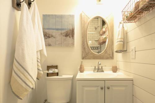 a bathroom with a sink and a toilet and a mirror at The Shoreline Container Home 12 min to Magnolia Silos and Baylor in Waco