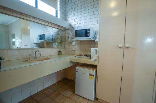 a small kitchen with a sink and a microwave at Paddlewheel Motel in Echuca