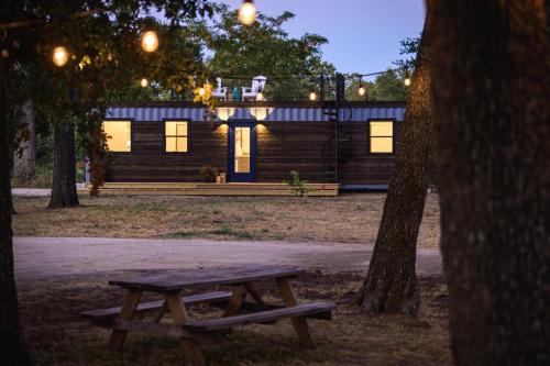 a wooden cabin with a picnic table in front of it at The Shoreline Container Home 12 min to Magnolia Silos and Baylor in Waco