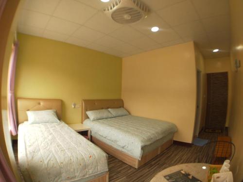 two beds in a room with yellow walls at 崗好山莊 in Jianshi