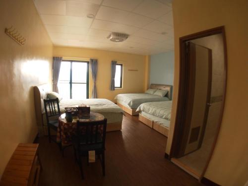 a room with two beds and a table and a mirror at 崗好山莊 in Jianshi