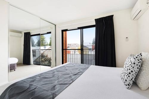 a bedroom with a bed and large glass windows at Parklane Apartments in Fremantle