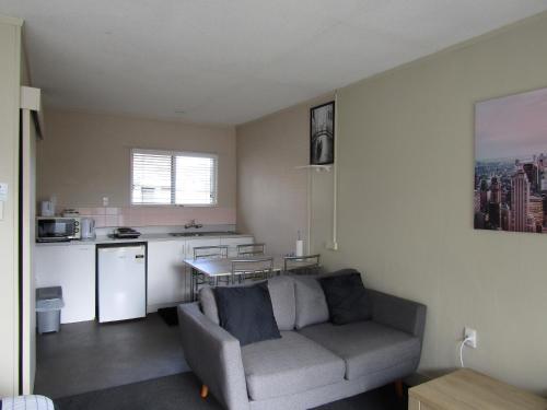 a living room with a couch and a kitchen at Anchorage Motel in Whitianga