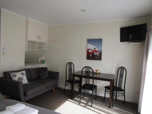 a living room with a couch and a table and chairs at Anchorage Motel in Whitianga