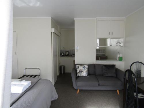 a living room with a couch and a kitchen at Anchorage Motel in Whitianga