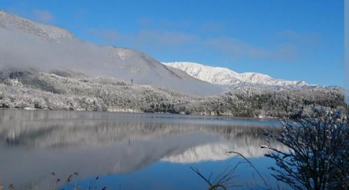 a view of a lake with snow covered mountains at プチホテル葡萄屋 in Hakuba