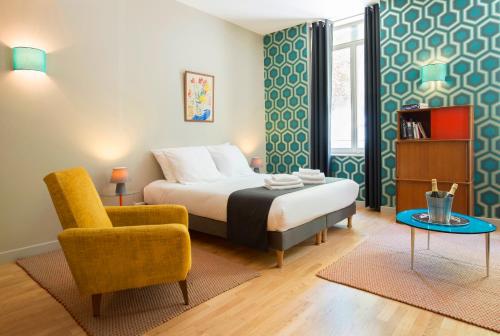 1 dormitorio con 1 cama, 1 silla y 1 mesa en Suites & Hôtel Helzear Champs-Elysées, en París