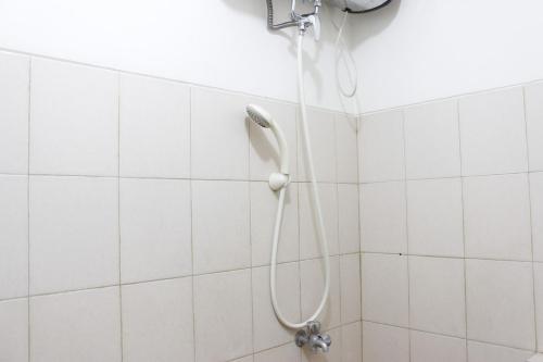 a shower in a white tiled bathroom at Cozy 2BR Tamansari Panoramic Apartment By Travelio in Bandung
