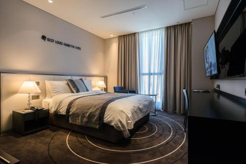 a hotel room with a bed and a large window at Best Louis Hamilton Hotel Changwon in Changwon