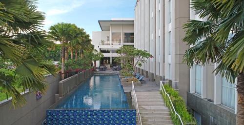 a swimming pool in the middle of a building with palm trees at Premier Place Surabaya Airport in Sidoarjo