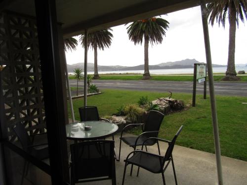 a patio with a table and chairs and a view of the ocean at Anchorage Motel in Whitianga