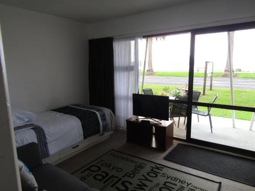 um quarto com uma cama, uma secretária e uma janela em Anchorage Motel em Whitianga
