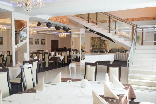 a restaurant with white tables and chairs and stairs at Talnakh Hotel in Talnakh