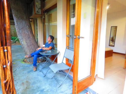 a woman sitting at a table next to a tree at Boulevard 251 Riverside Apartments in Iquitos