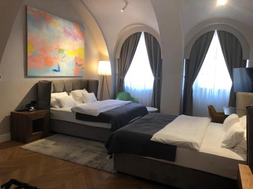 two beds in a bedroom with arched windows at Boutique hotel Tvrđa in Osijek