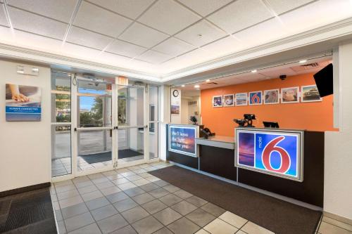 a waiting room with a tv and a sign on a wall at Motel 6-Orlando, FL - International Dr in Orlando
