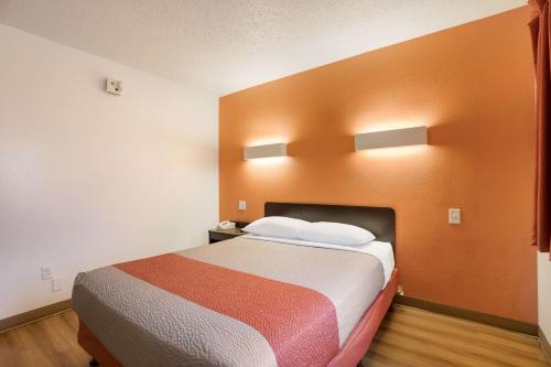 a large bed in a room with orange walls at Motel 6-Orlando, FL - International Dr in Orlando