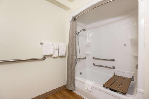 a bathroom with a tub and a shower with towels at Motel 6-Orlando, FL - International Dr in Orlando