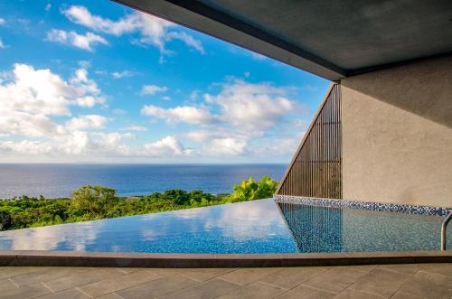 a view of the ocean from a house with a swimming pool at Hanalee Villa Kouri in Nakijin