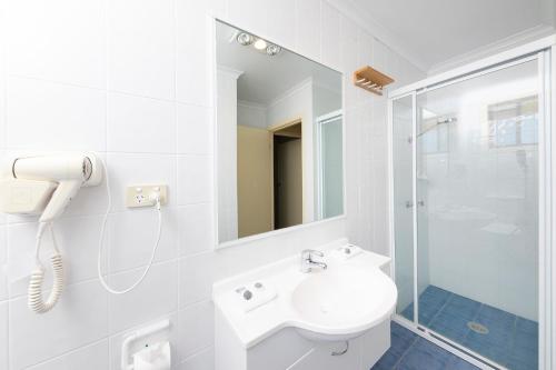 a white bathroom with a sink and a shower at Seashells Beachfront Resort in Diamond Beach