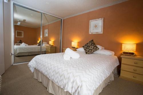 una camera d'albergo con un grande letto e uno specchio di Northpoint Holiday Apartments ad Alexandra Headland