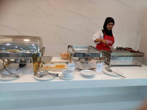 a woman standing in a kitchen preparing food at Alfahad Hotel in Hat Yai