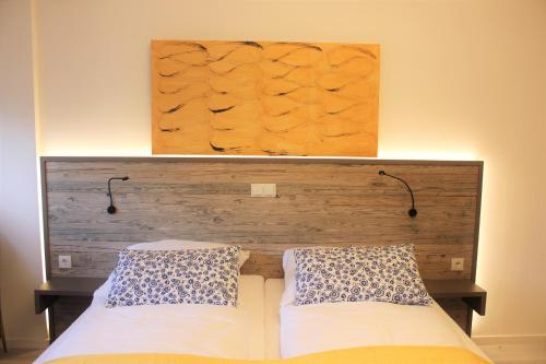 a bed with a wooden headboard and two pillows at City Hotel Bamberg in Bamberg