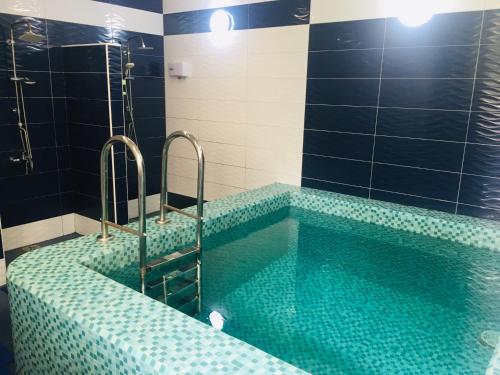 a bathroom with a swimming pool with blue tiles at Brigantina Hotel in Khabarovsk
