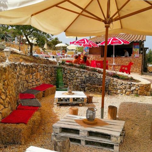 a patio with tables and chairs and an umbrella at B&B Badde Cubas in Usini