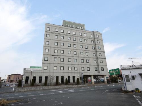 a tall white building with a sign on top of it at Hotel Route-Inn Kakegawa Inter in Kakegawa