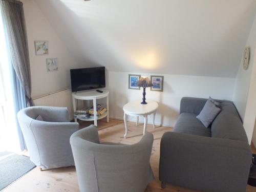 a living room with a couch and chairs and a tv at Pension Lærkelill in Skovlund
