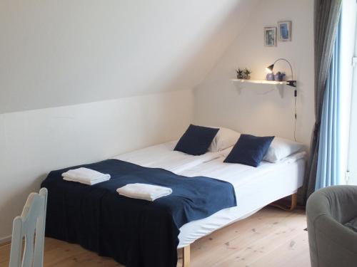a bedroom with a bed with blue and white sheets at Pension Lærkelill in Skovlund
