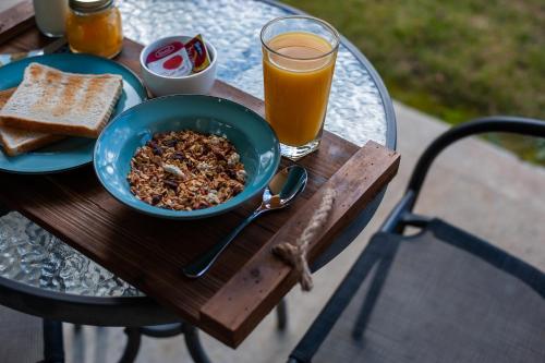 a table with a bowl of cereal and toast and a glass of orange juice at Carrick Lodge Motel in Cromwell