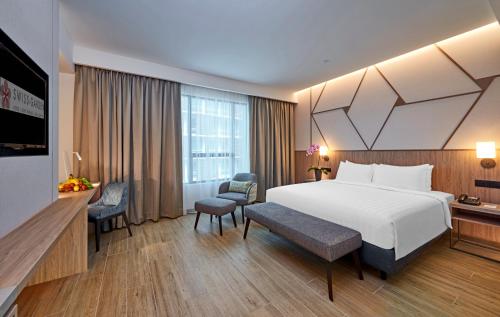 um quarto de hotel com uma grande cama branca e uma secretária em Swiss-Garden Hotel Bukit Bintang Kuala Lumpur em Kuala Lumpur