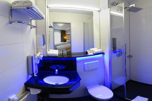 a bathroom with a blue sink and a toilet at Best Western Hotel Braunschweig in Braunschweig