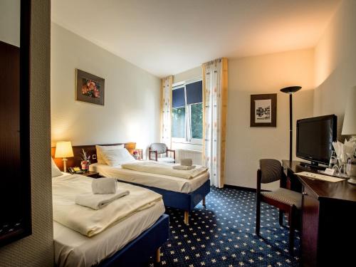 a hotel room with two beds and a television at Parkhotel Papenburg in Papenburg