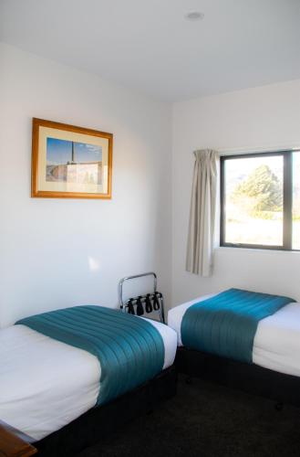 two beds in a room with two windows at Carrick Lodge Motel in Cromwell
