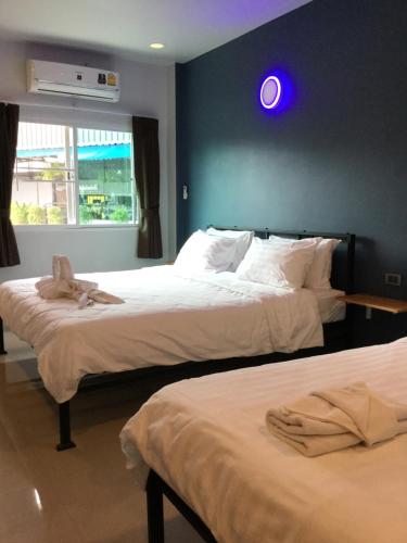 two beds in a room with a blue light on the wall at Chan Place Hotel in Nakhon Ratchasima