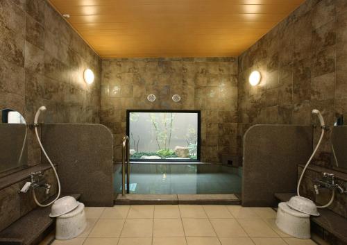 a bathroom with a swimming pool with two toilets at Hotel Route-Inn Handakamezaki in Handa