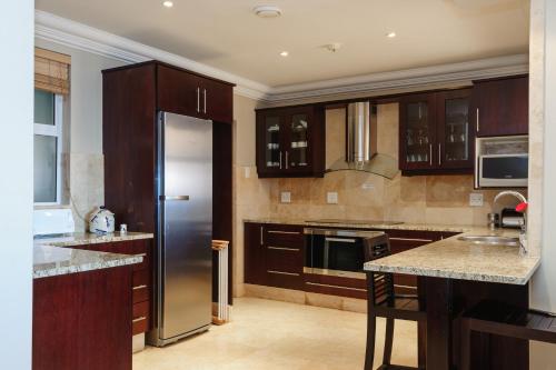 eine Küche mit Holzschränken und einem Kühlschrank aus Edelstahl in der Unterkunft Ballito Manor Beach 405 - FAMILY ONLY - With Generator in Ballito