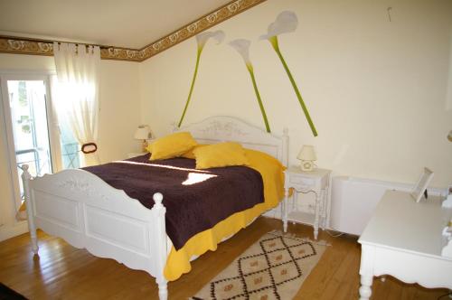 a bedroom with a white bed with yellow sheets at La Cognée in Cugnaux