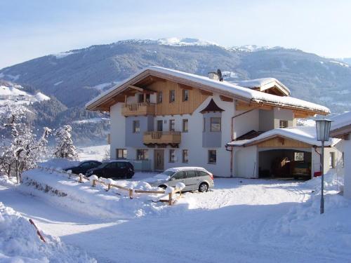 een huis met twee auto's in de sneeuw bij Wöscherhof in Kaltenbach